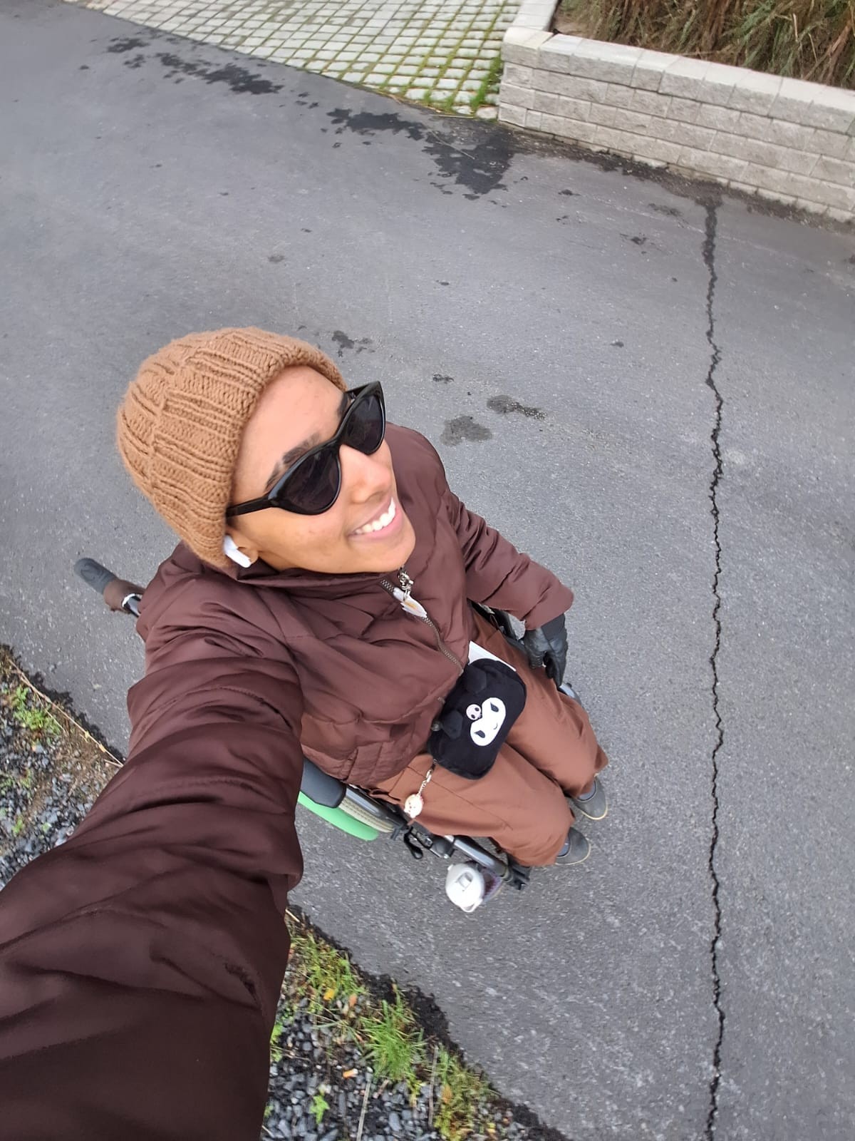 GetImage Lyhytkasvuinen nainen, tummansinisessä mekossa. Taustalla kukkaseinä.